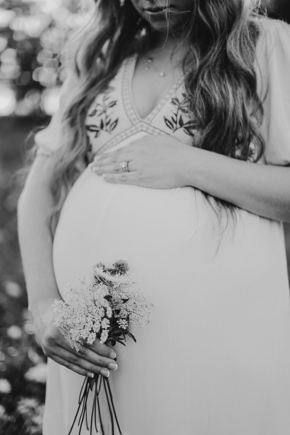 A black and white image showing someone holding a delicate bouquet of flowers.