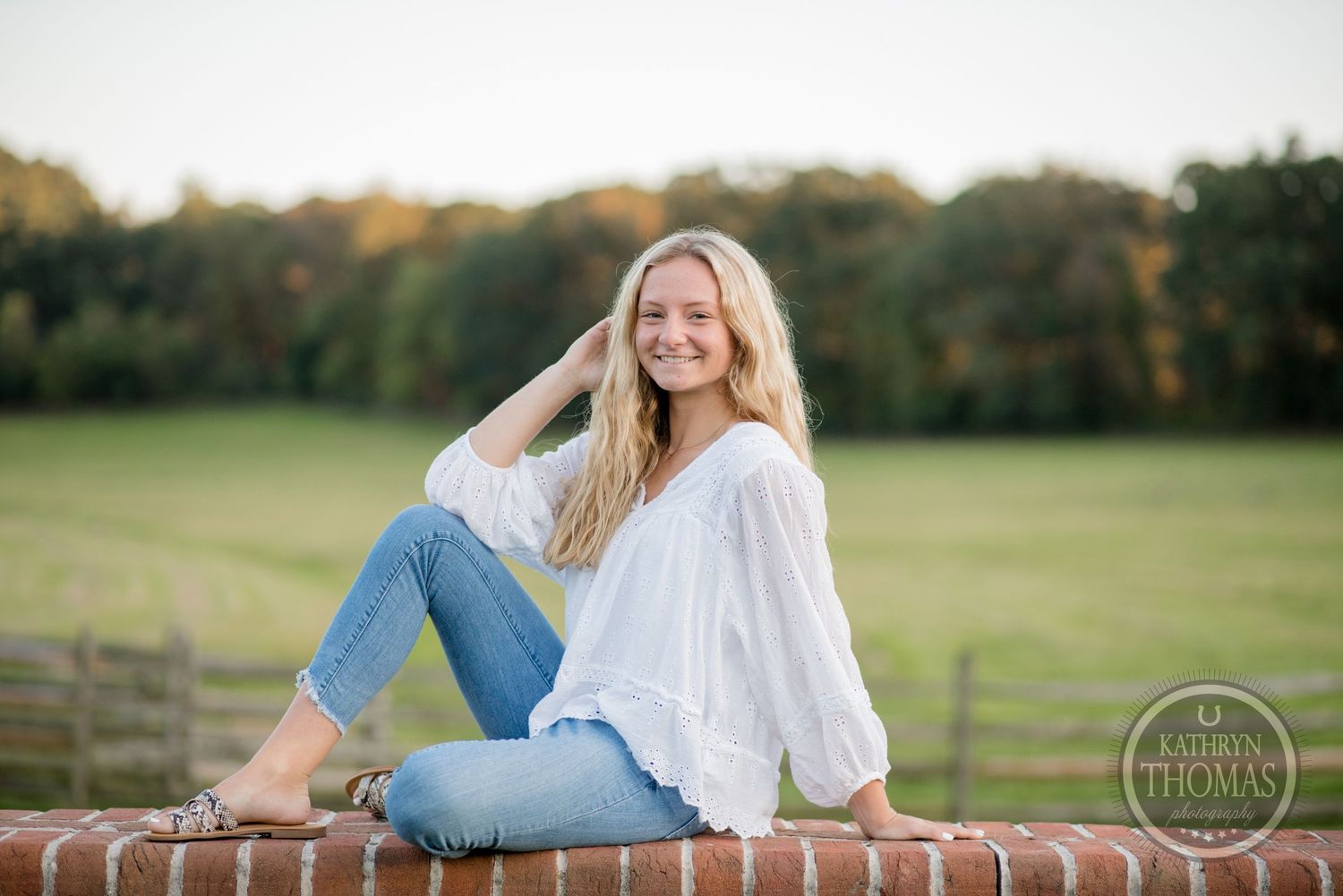 Sunset portrait on brick wall featuring flowing white top and relaxed denim style.