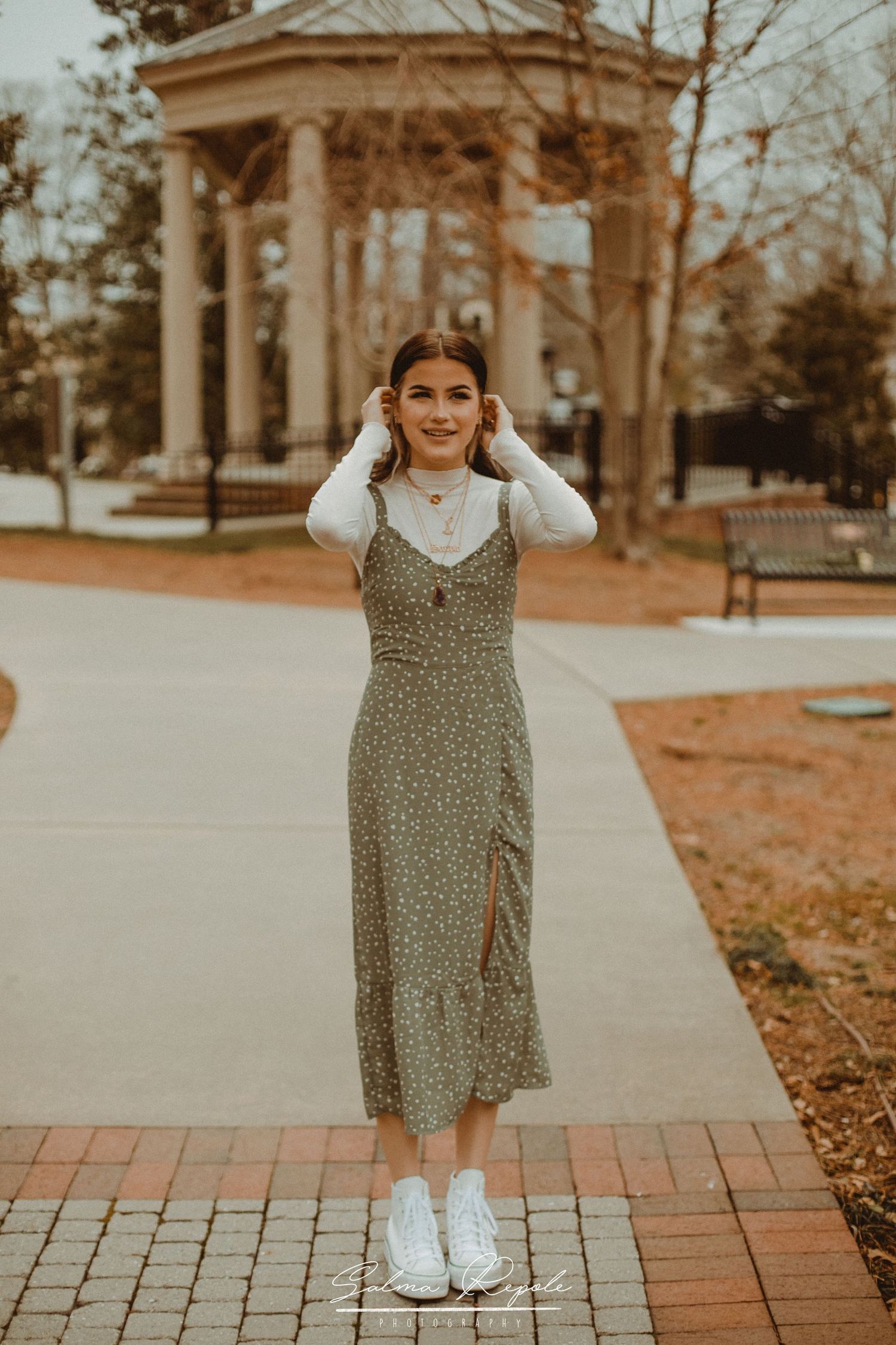 Casual outdoor portrait near a classical gazebo with brick pathways.