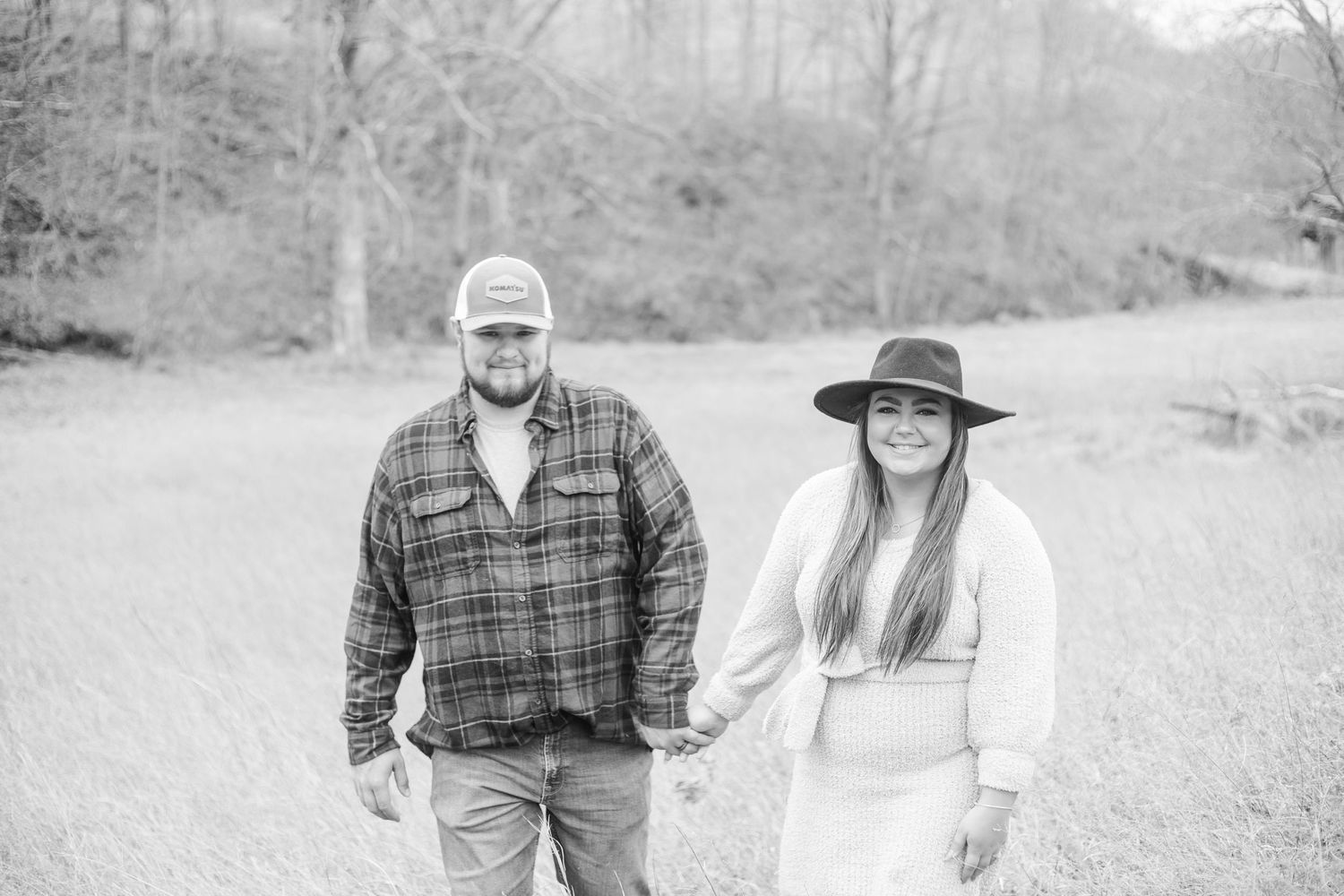A couple shares a tender moment in a rustic outdoor setting with fall foliage.