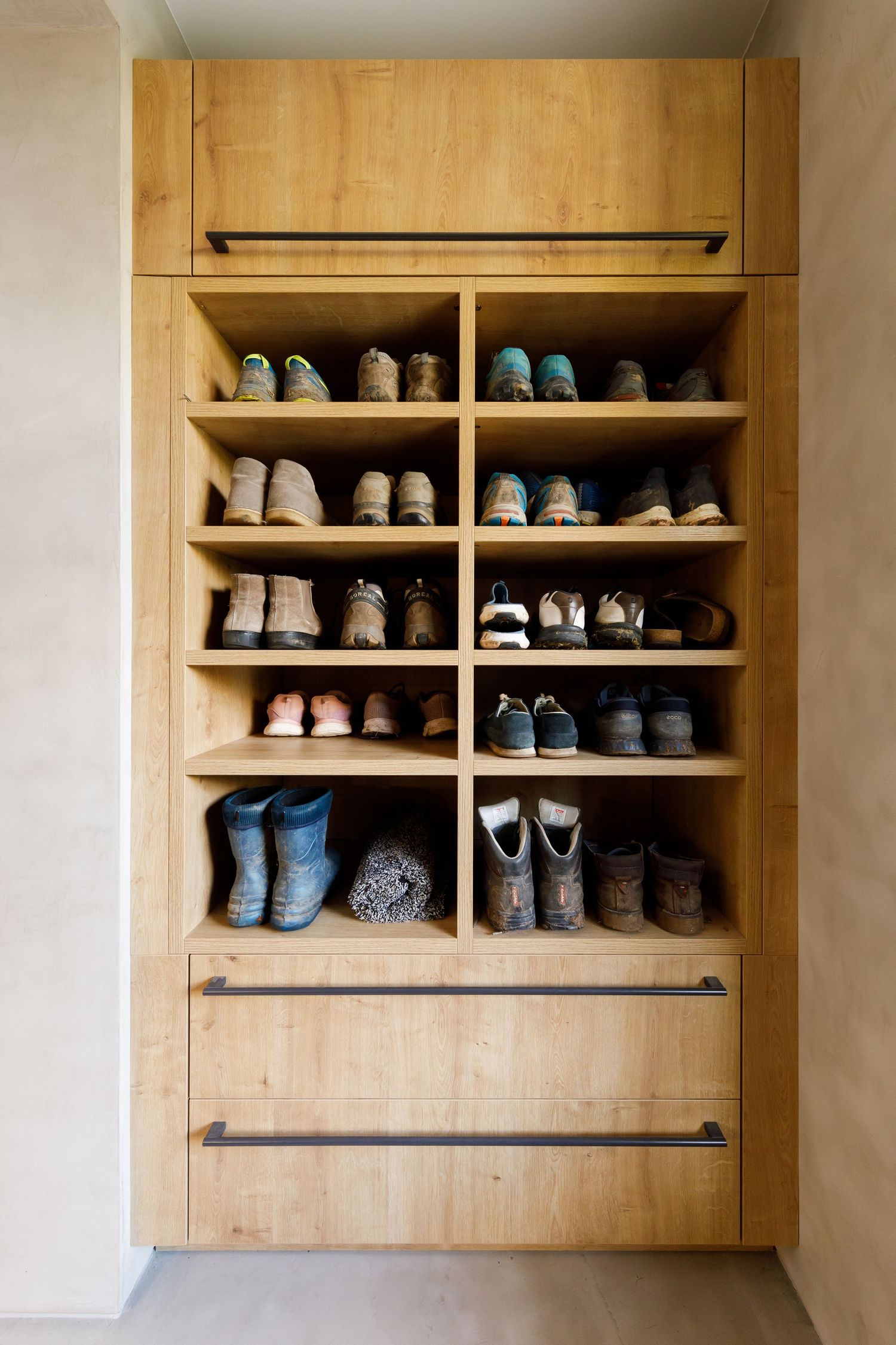 Built-in wooden shoe storage cabinet with multiple shelves displaying organized footwear collection taken during an interiors photoshoot.