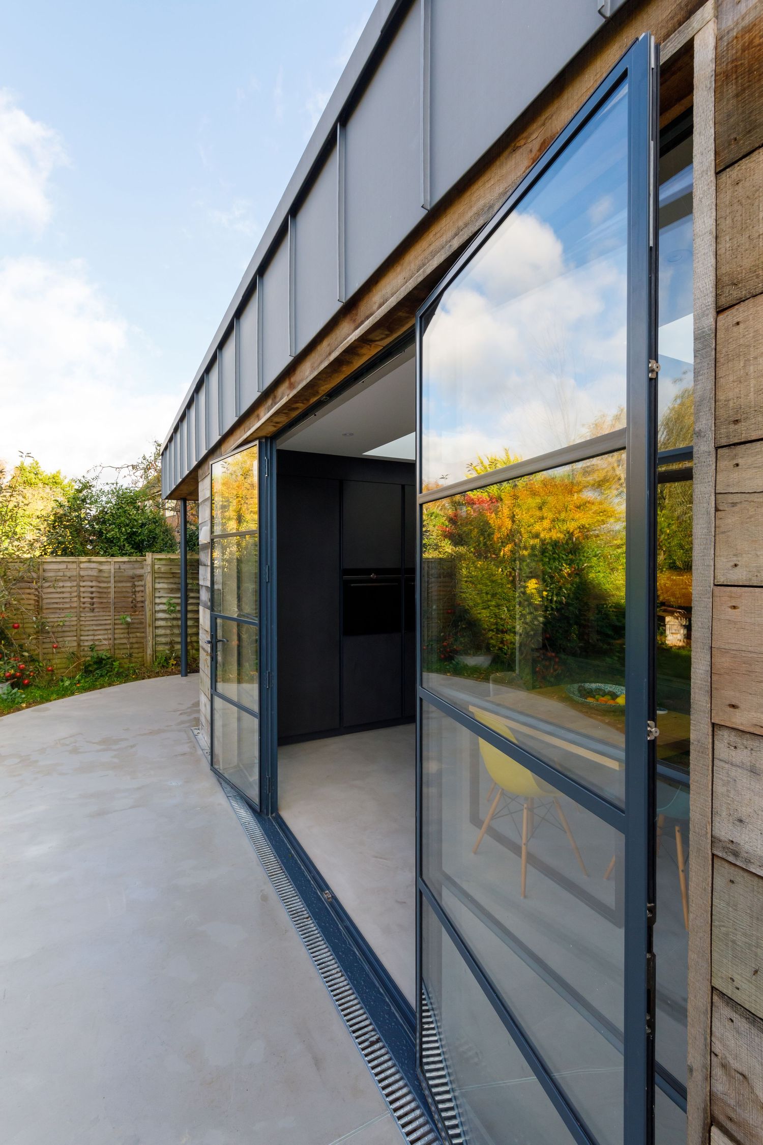 Modern glass sliding doors with metal frames leading to concrete patio and garden space taken during an interiors photoshoot.