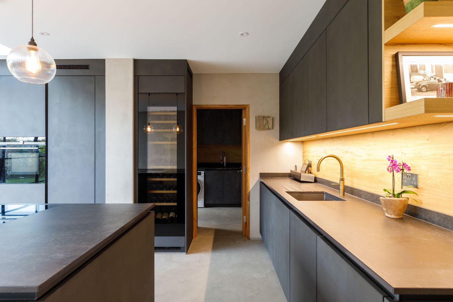 Contemporary dark kitchen with minimalist design featuring built-in appliances and under-cabinet lighting taken during an interiors photosh.