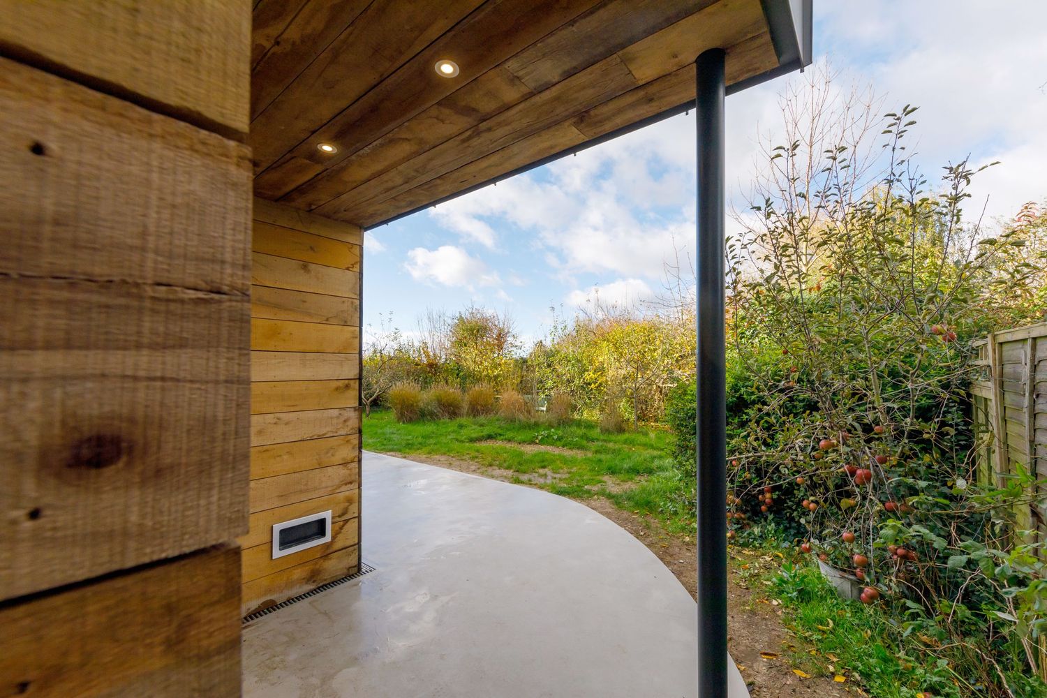 Modern covered patio entrance with curved concrete path leading to garden landscape taken during an interiors photoshoot.