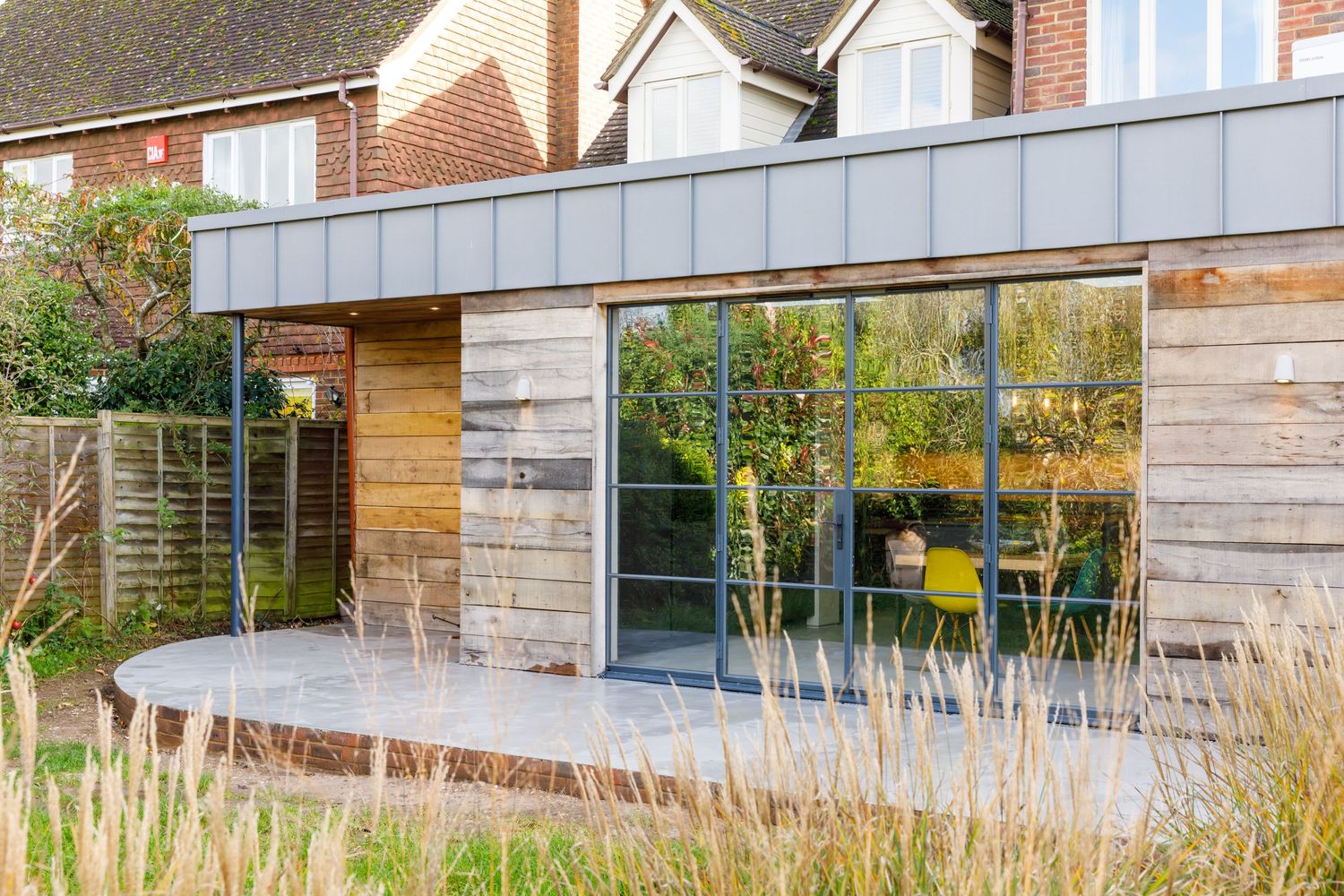 Contemporary house extension with wood cladding and large glass windows reflecting garden views taken during an interiors photoshoot.