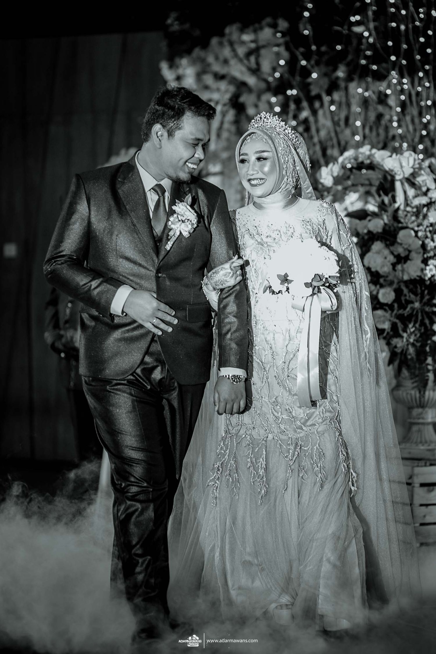 An elegant wedding couple poses together amidst decorative smoke effects and twinkling lights.