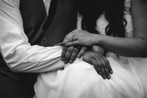 Black and white close-up of newlyweds' hands resting together.