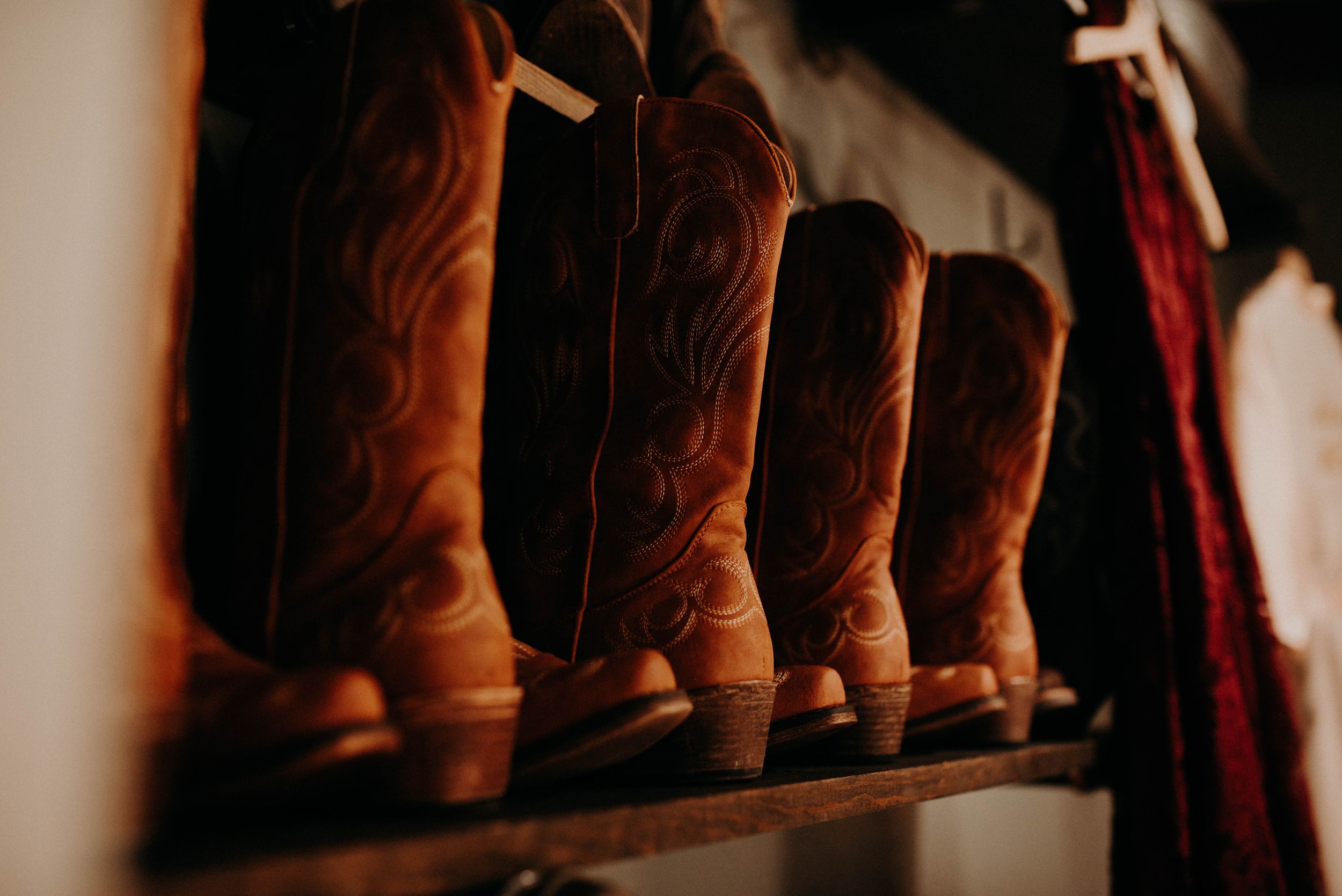 A row of brown leather cowboy boots lined up on a shelf.