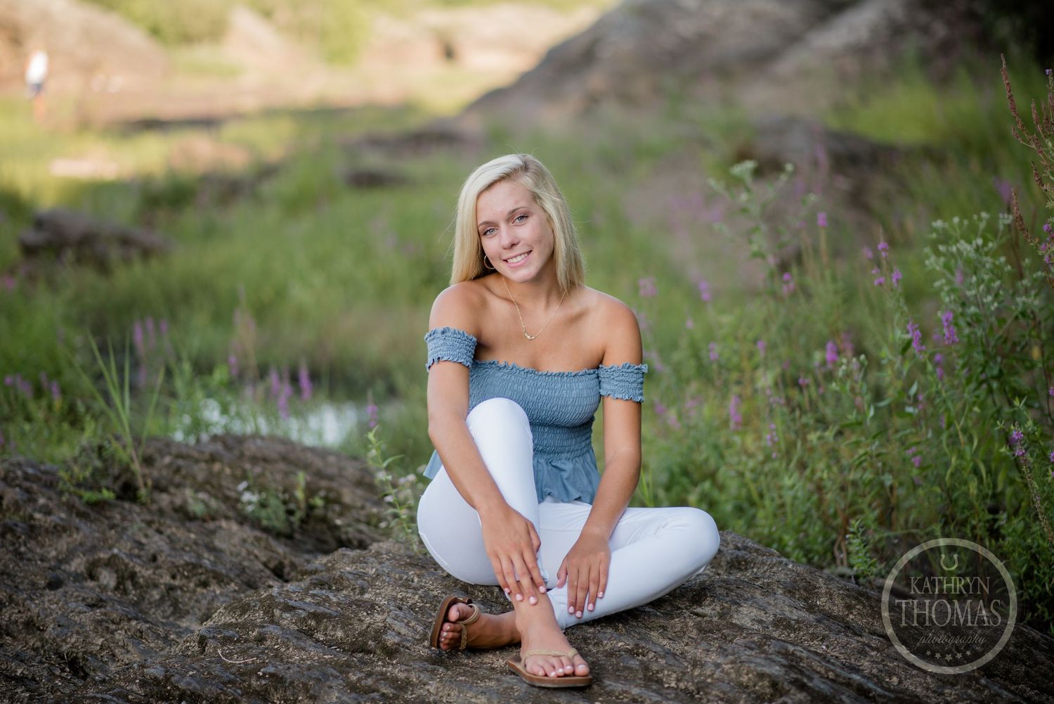 Casual summer portrait with someone wearing blue off-shoulder top and white pants outdoors.