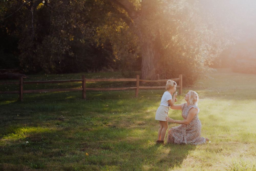 A family enjoying a golden sunset moment together on a grassy hill with beautiful backlit lighting.