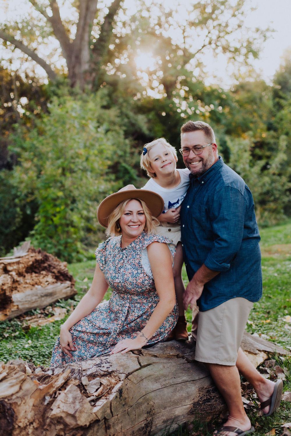 A joyful family poses together on a fallen log during a golden hour photo session.