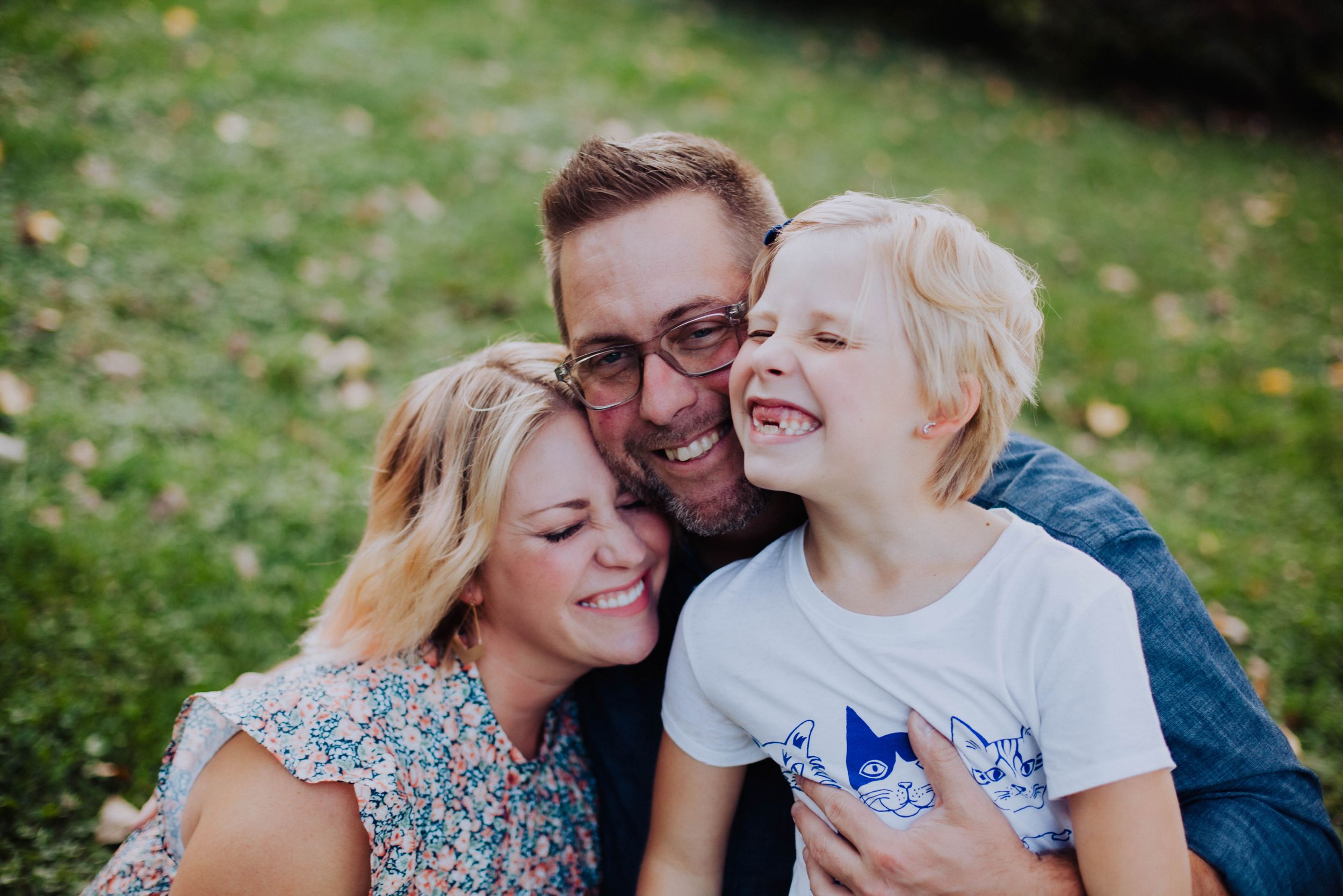 A tender family moment captured during golden hour in a grassy outdoor setting.