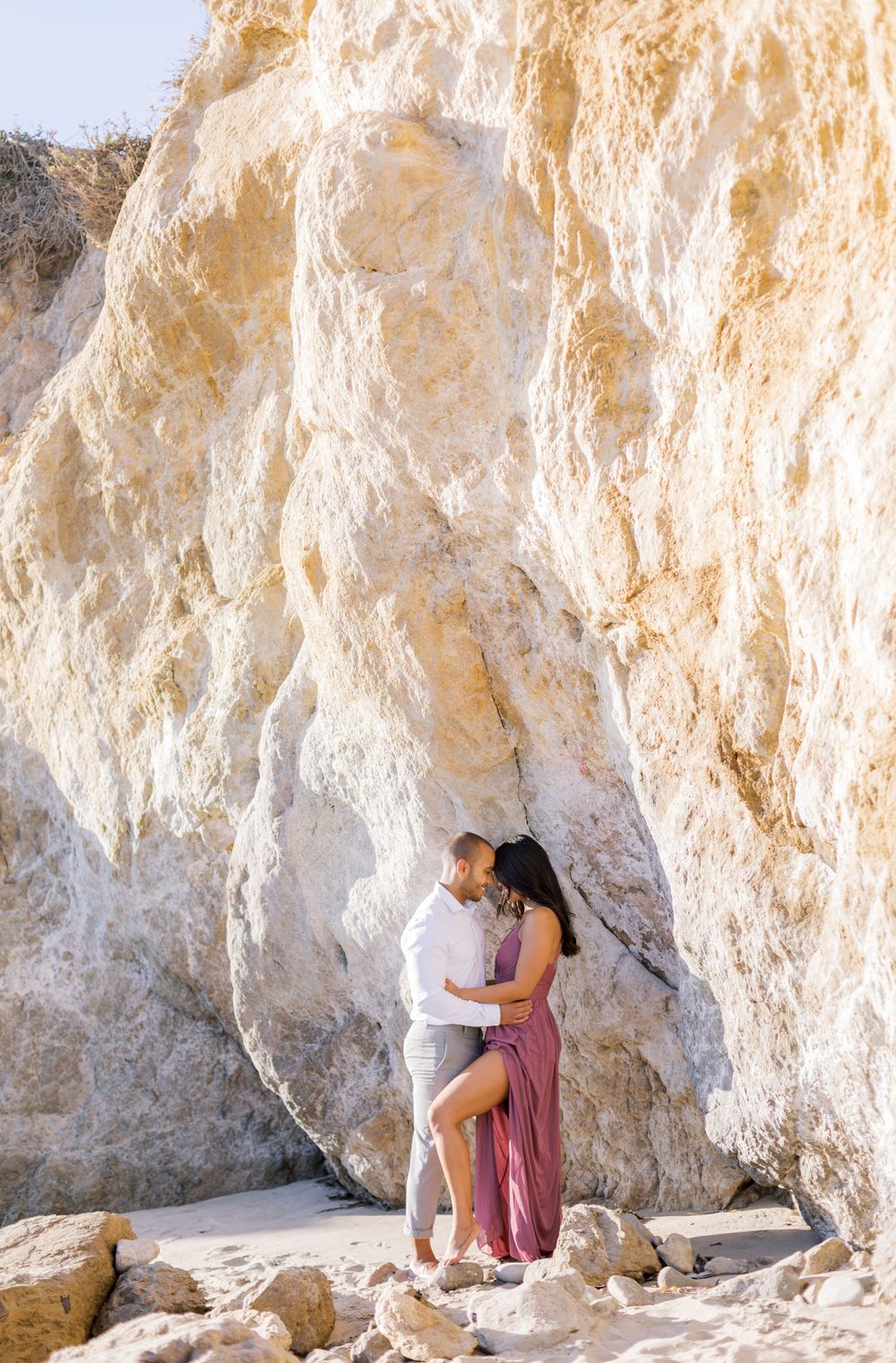 A couple shares an intimate embrace beneath towering white limestone cliffs.