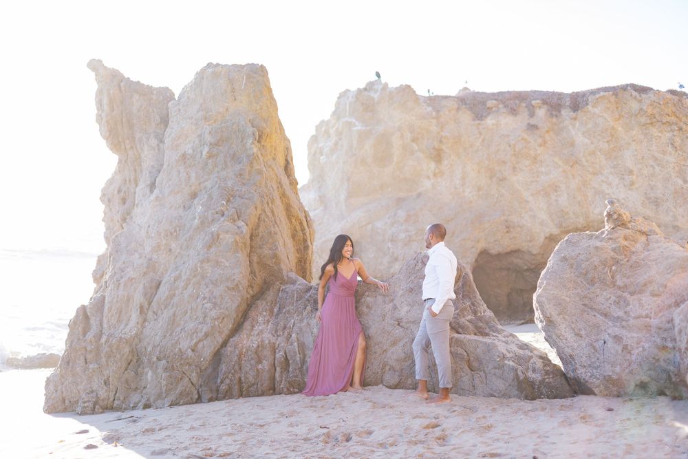 Couple walking among dramatic coastal rock formations at sunset.