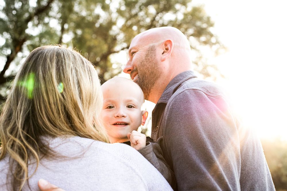 Sunlit outdoor family photography session with natural expressions and laughter.
