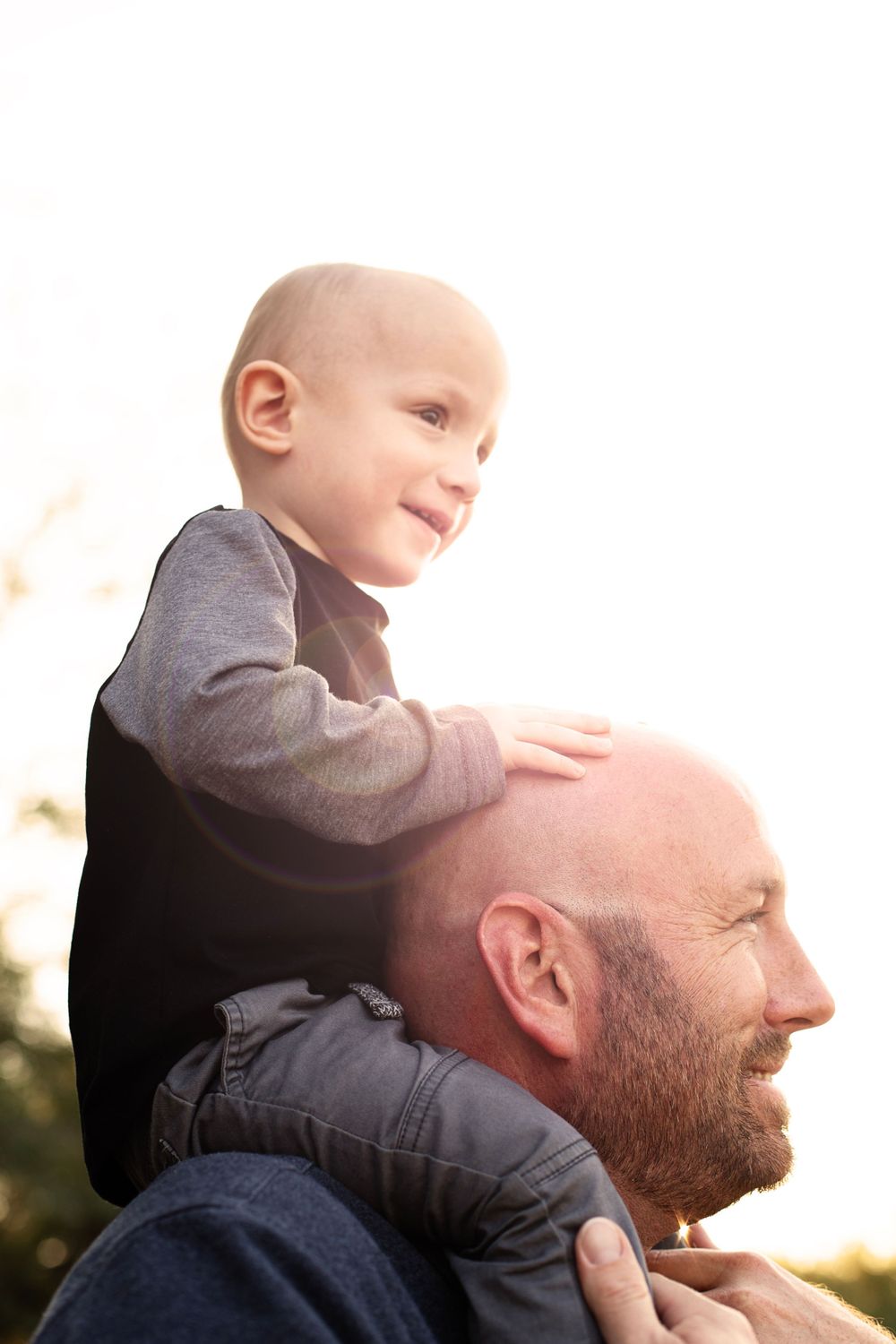 A parent and toddler share a playful moment outdoors during golden hour.