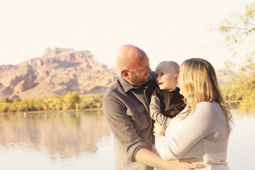 Family shares tender moments during sunset photoshoot by mountain lake.