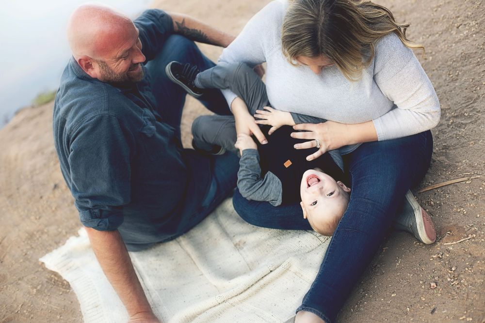 Casual family photo session on blanket with desert scenery.