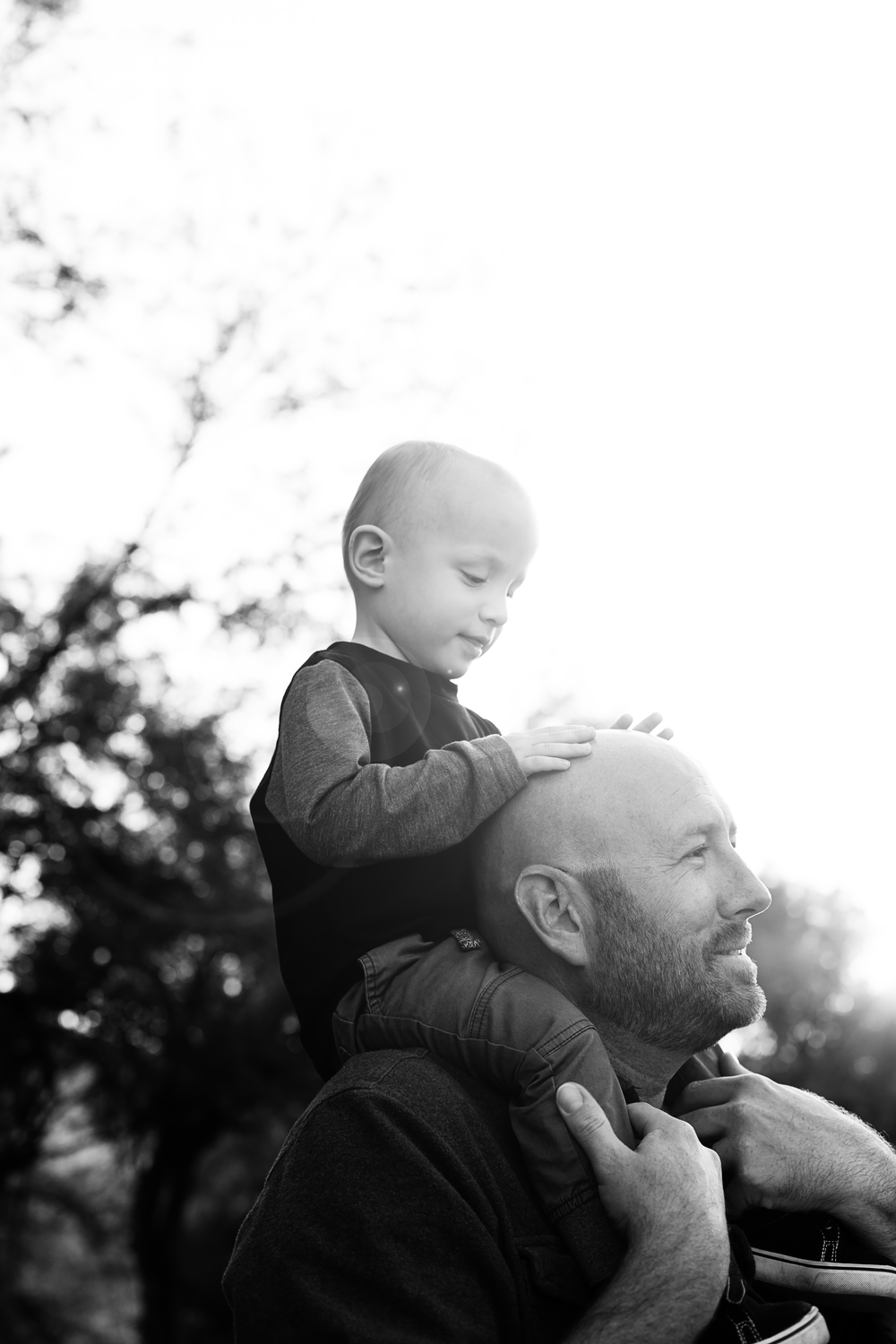 Black and white portrait of a parent and child enjoying a tender moment in nature.