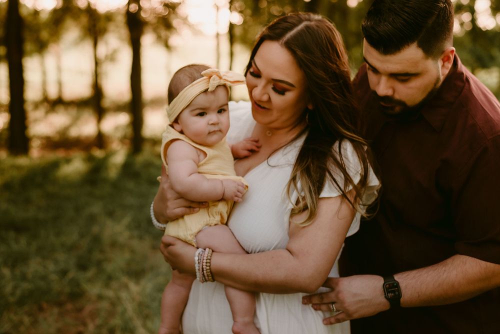 An intimate family portrait in warm sunset lighting with their small child.