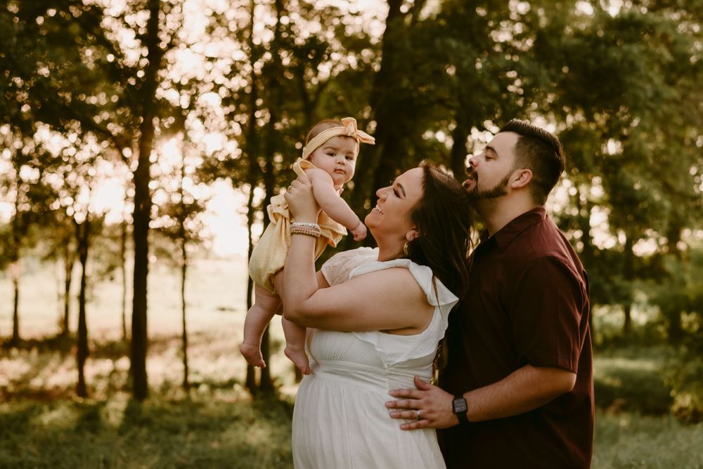 A happy family shares laughter and joy during their sunset photo session in a field.