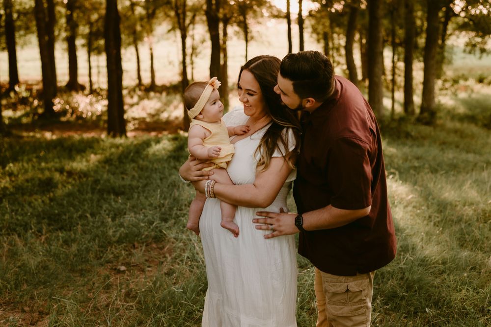 A tender family moment captured in golden sunlight filtering through trees.