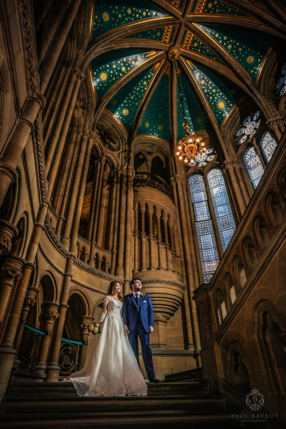 Couple stands beneath stunning vaulted ceiling with celestial painted details.