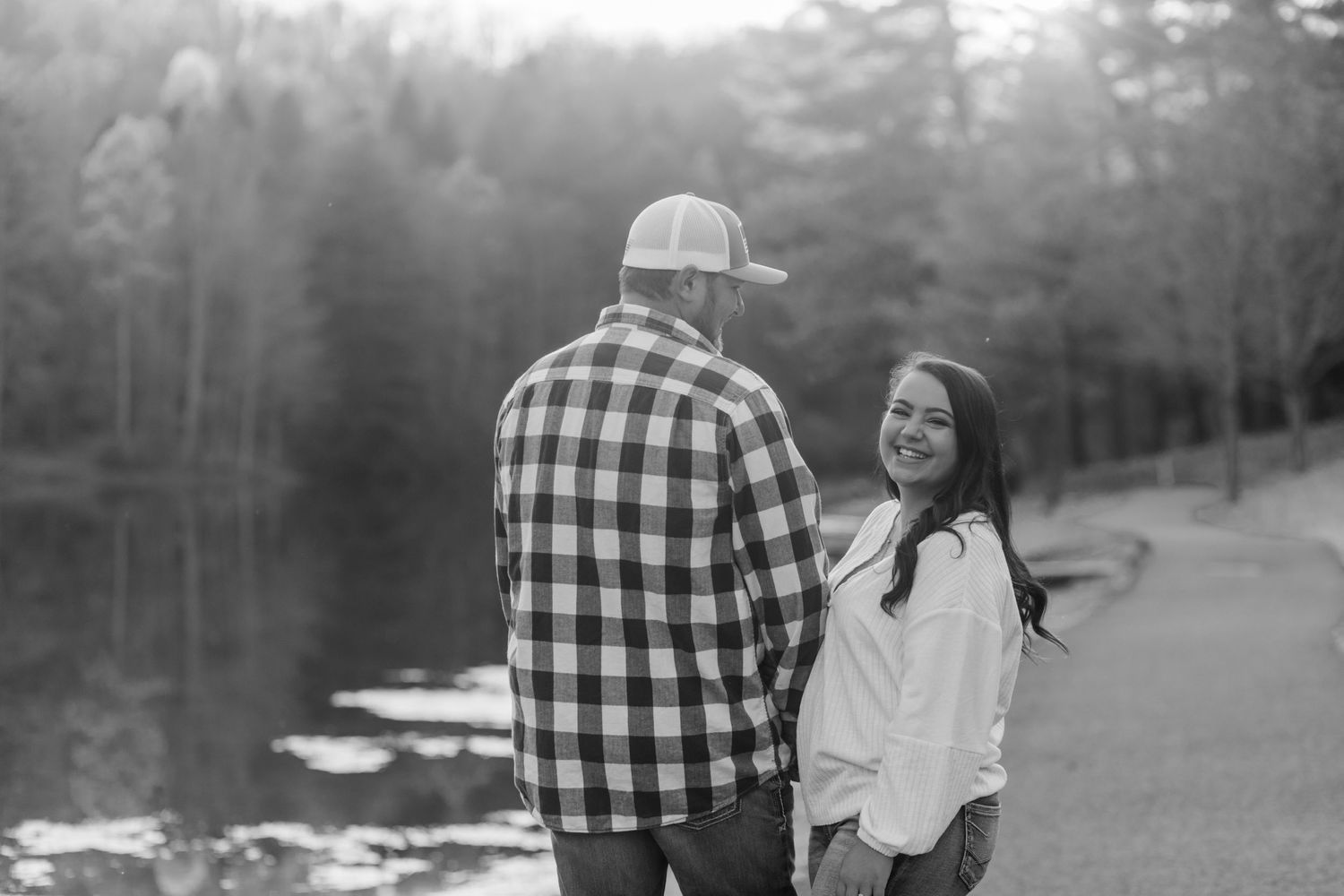 Black and white portrait of couple by lake with plaid shirt and white sweater outfits.