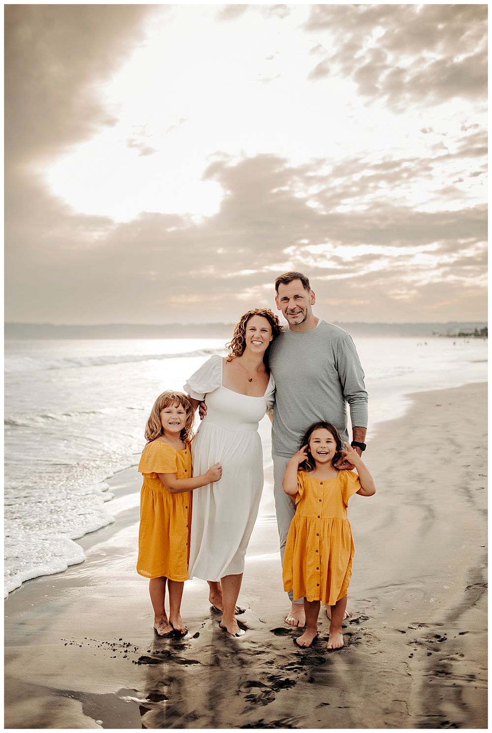 sun shines behind family gathered on the beach by Danielle Miranda Photography