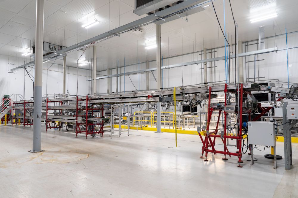 Large industrial production area with machinery and equipment in a bright warehouse setting.
