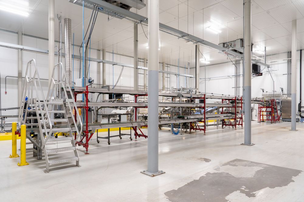 Modern manufacturing facility with clean white walls and industrial equipment setup.