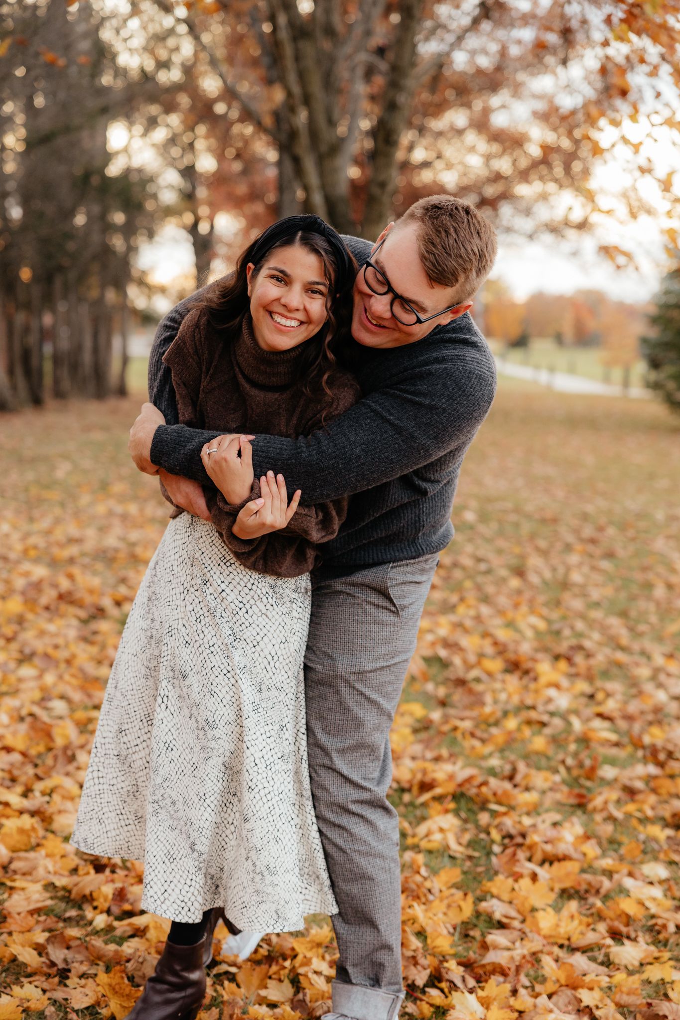 Couple shares playful and romantic moments among fallen autumn leaves.