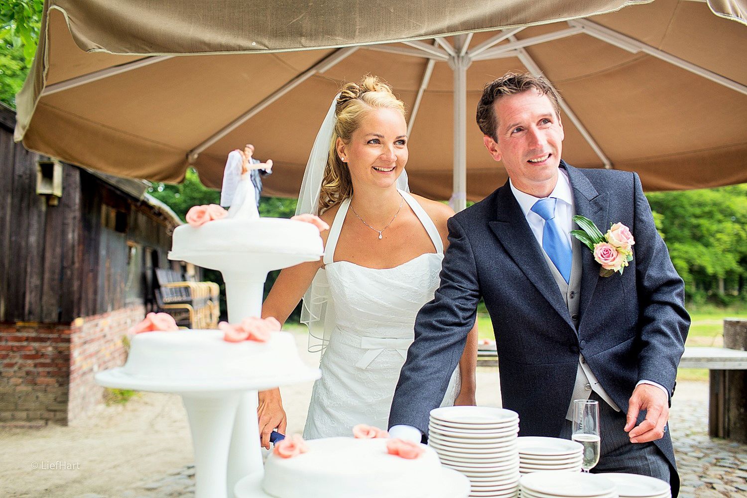 Newlyweds cutting their wedding cake at an outdoor reception.