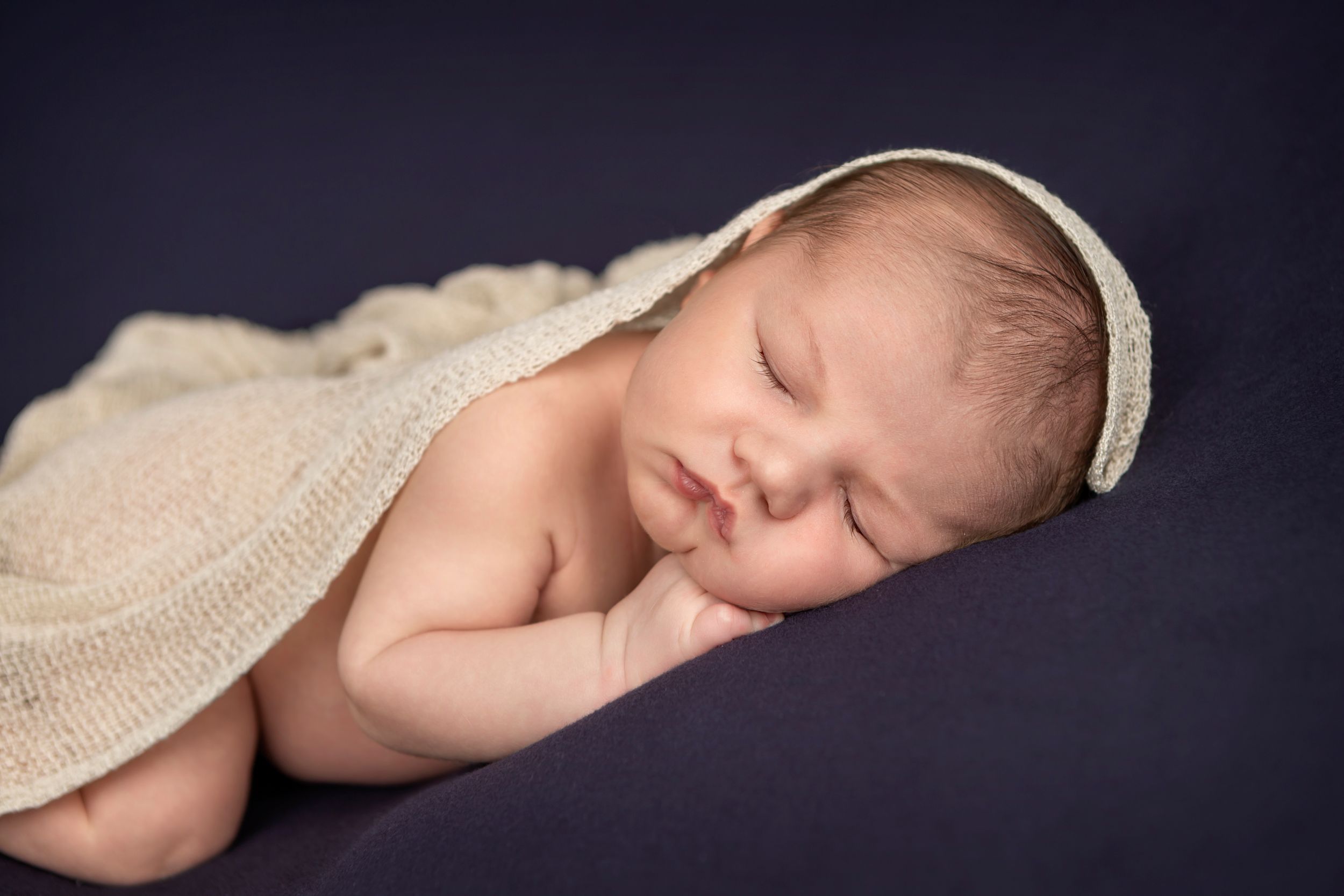 Sleeping baby boy wrapped in dark cream wrap