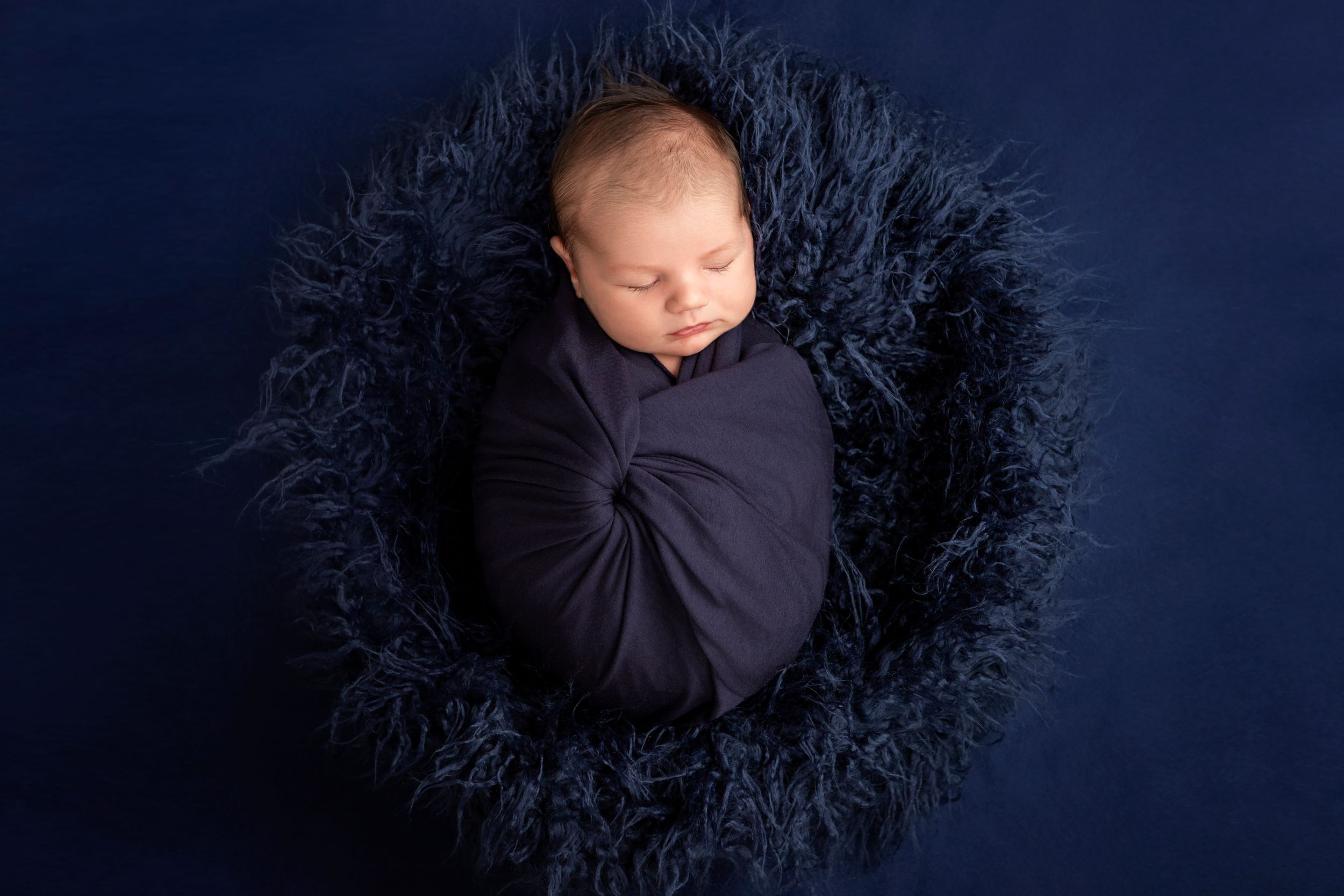 Sleeping baby boy wrapped in dark navy blue