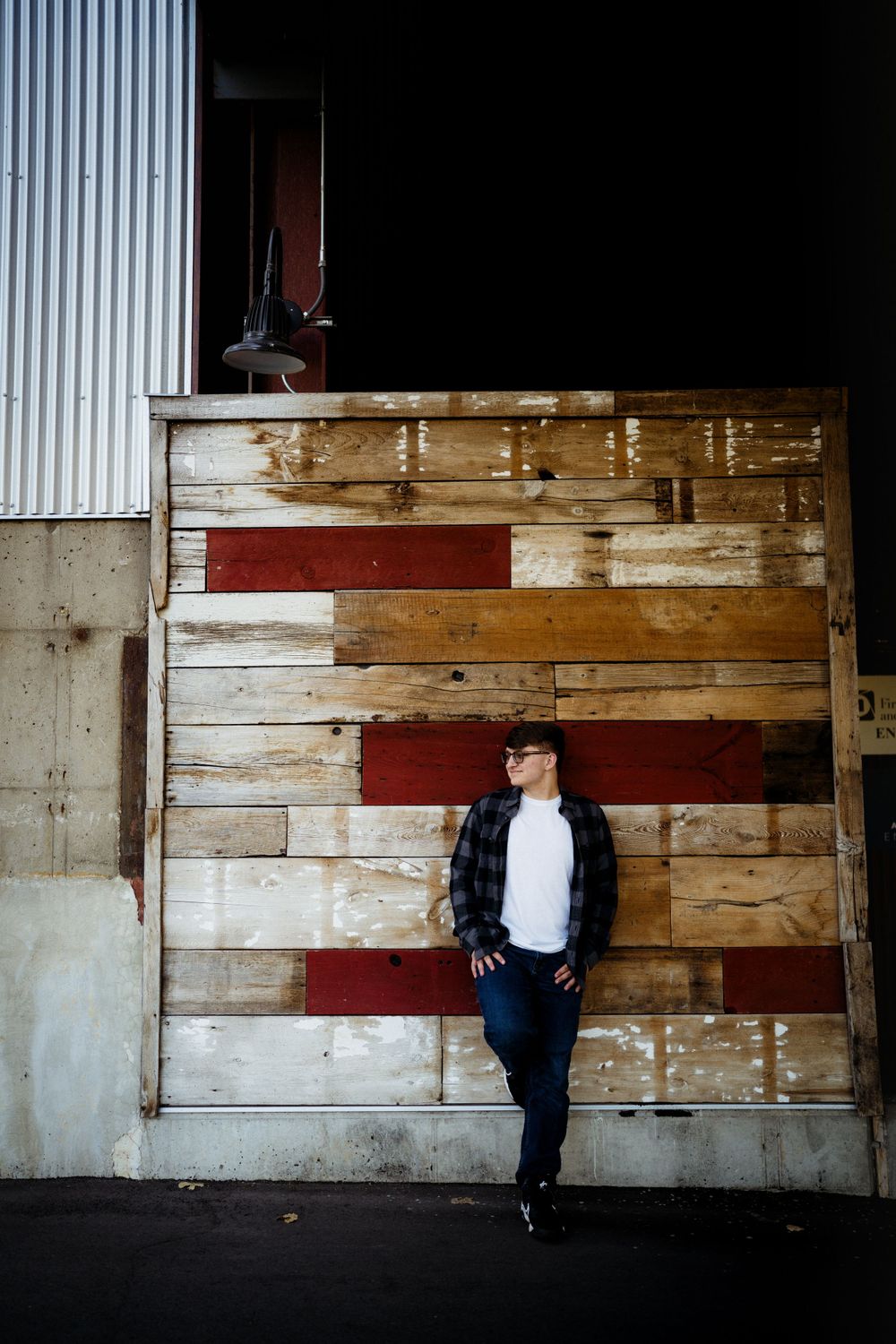 Urban fashion shoot against rustic wooden wall with red stripes in industrial setting.