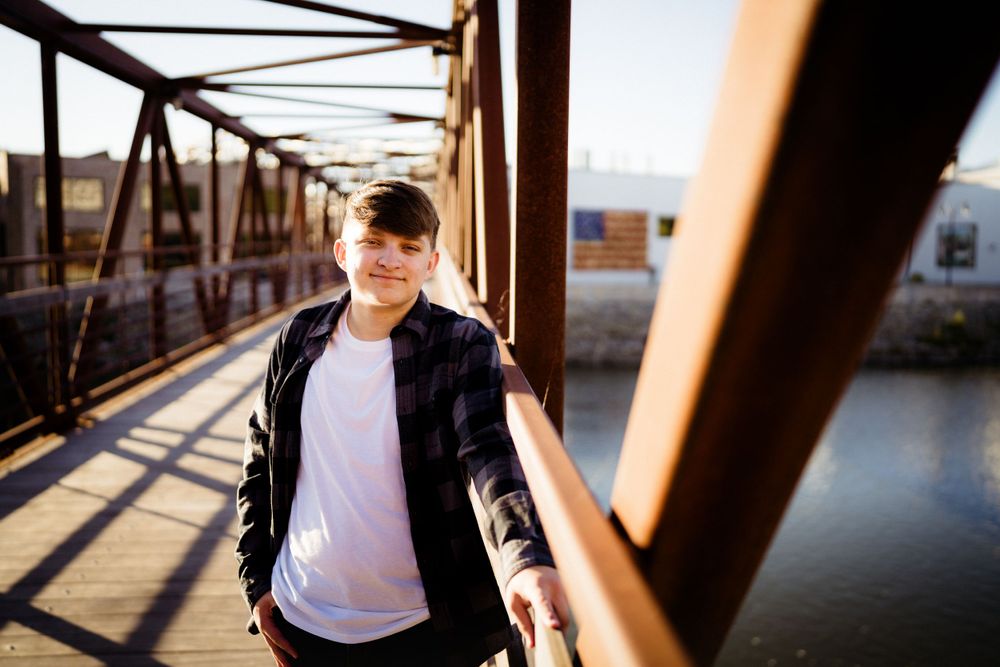 Person walks along rustic bridge with metal beams creating leading lines.