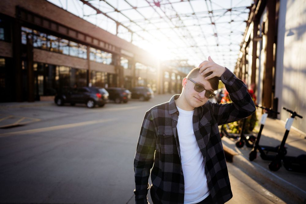 Person shields eyes from sunlight on urban street during golden hour.