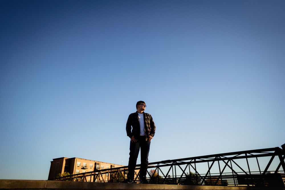 Silhouetted figure stands atop metal structure against deep blue sky.