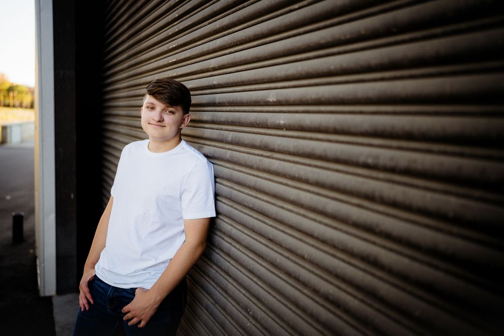 Portrait against industrial corrugated metal wall with moody lighting and dramatic shadows.