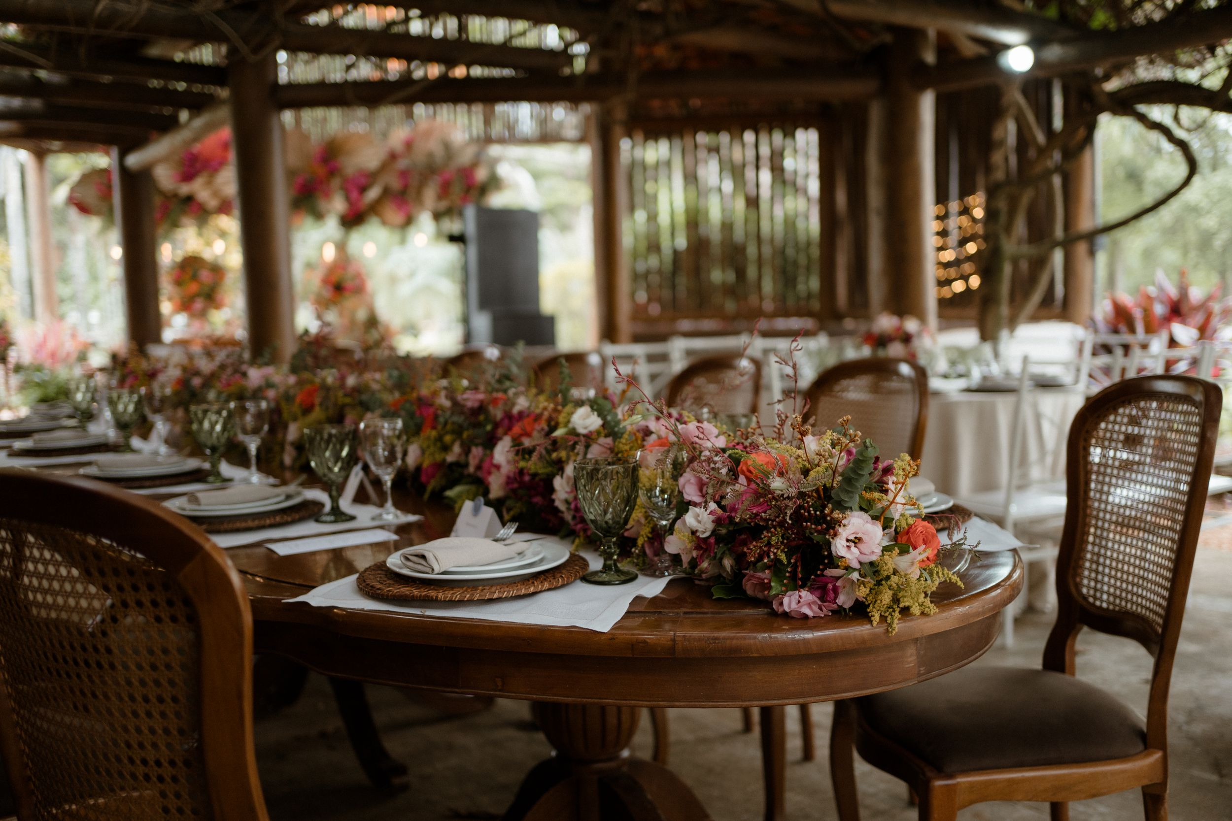 Elegant wedding reception table set with floral centerpieces and vintage cane-back chairs.