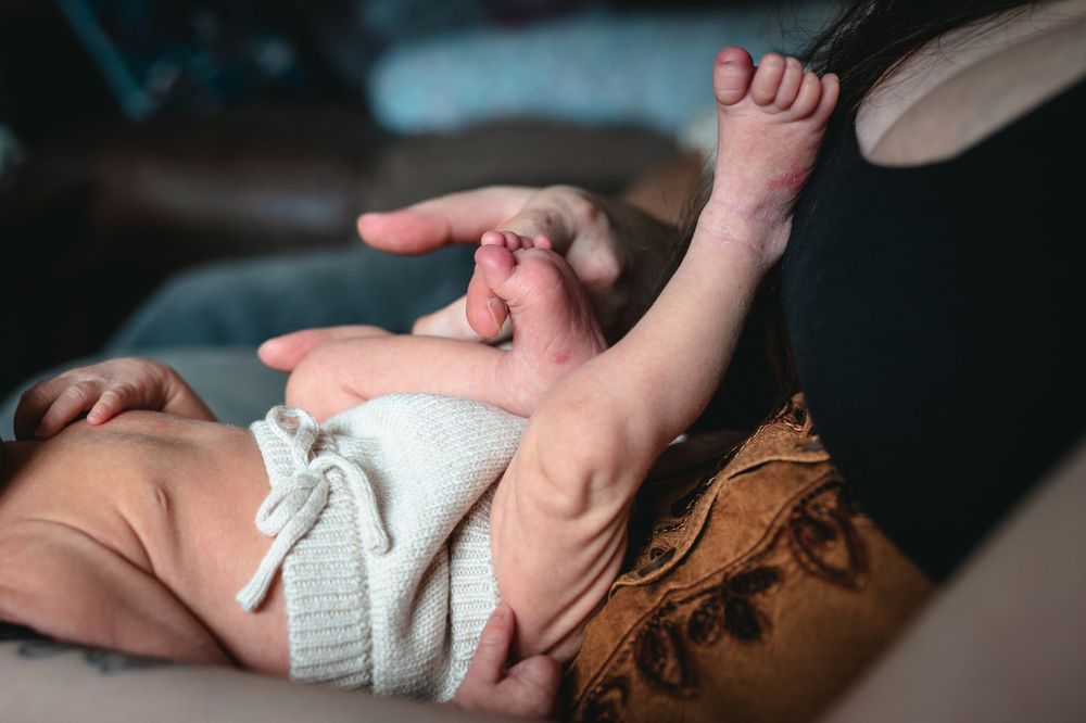 newborn baby feet in the air on Mum's knee