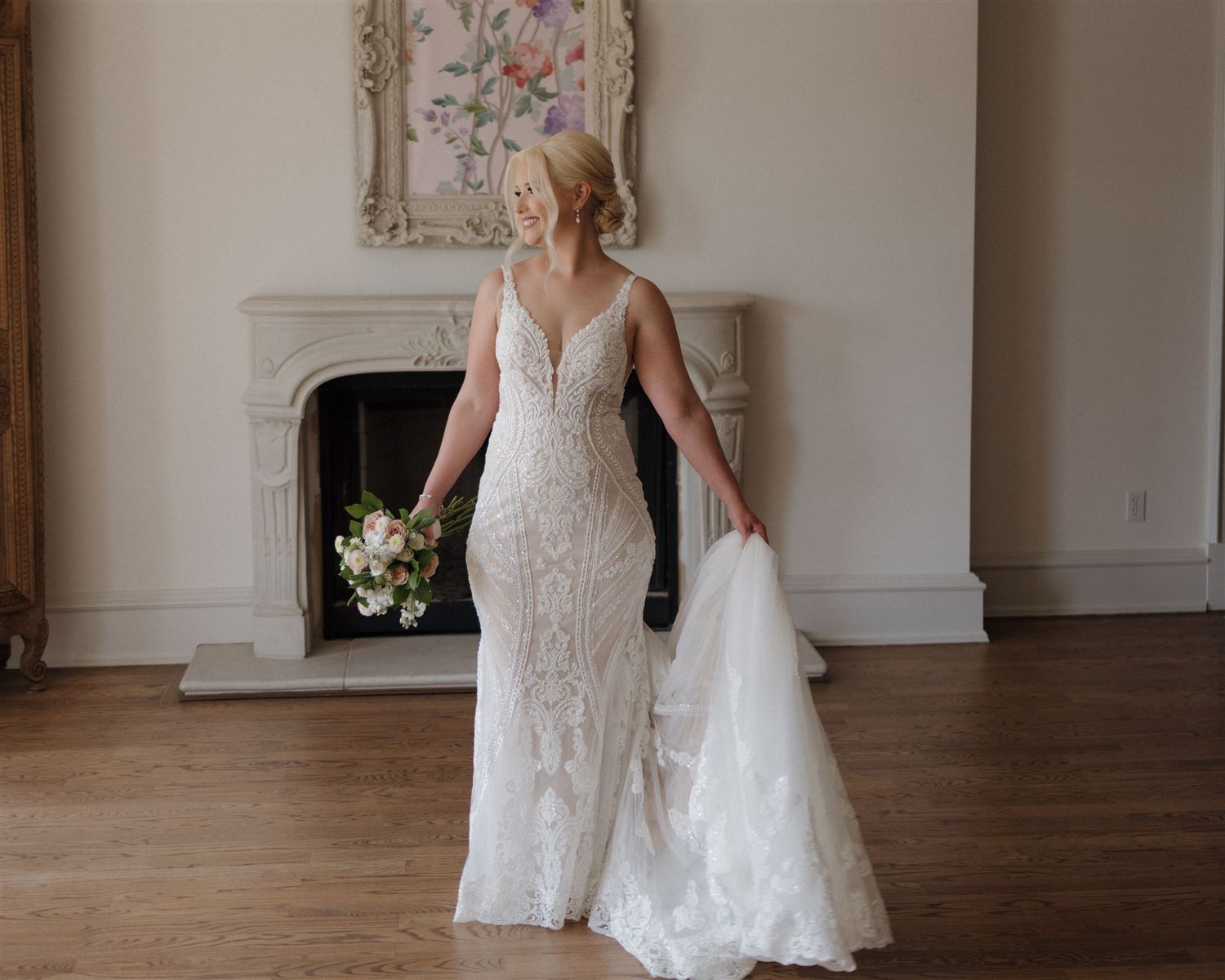 Bridal portrait showcasing the movement of a lace wedding gown near an ornate fireplace.