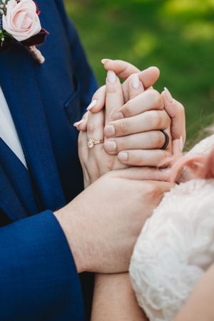ring photo of bride and groom holding hands