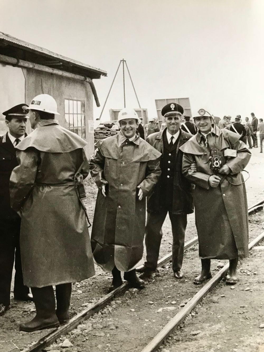 Workers and officials gathered along railroad tracks in vintage industrial scene.