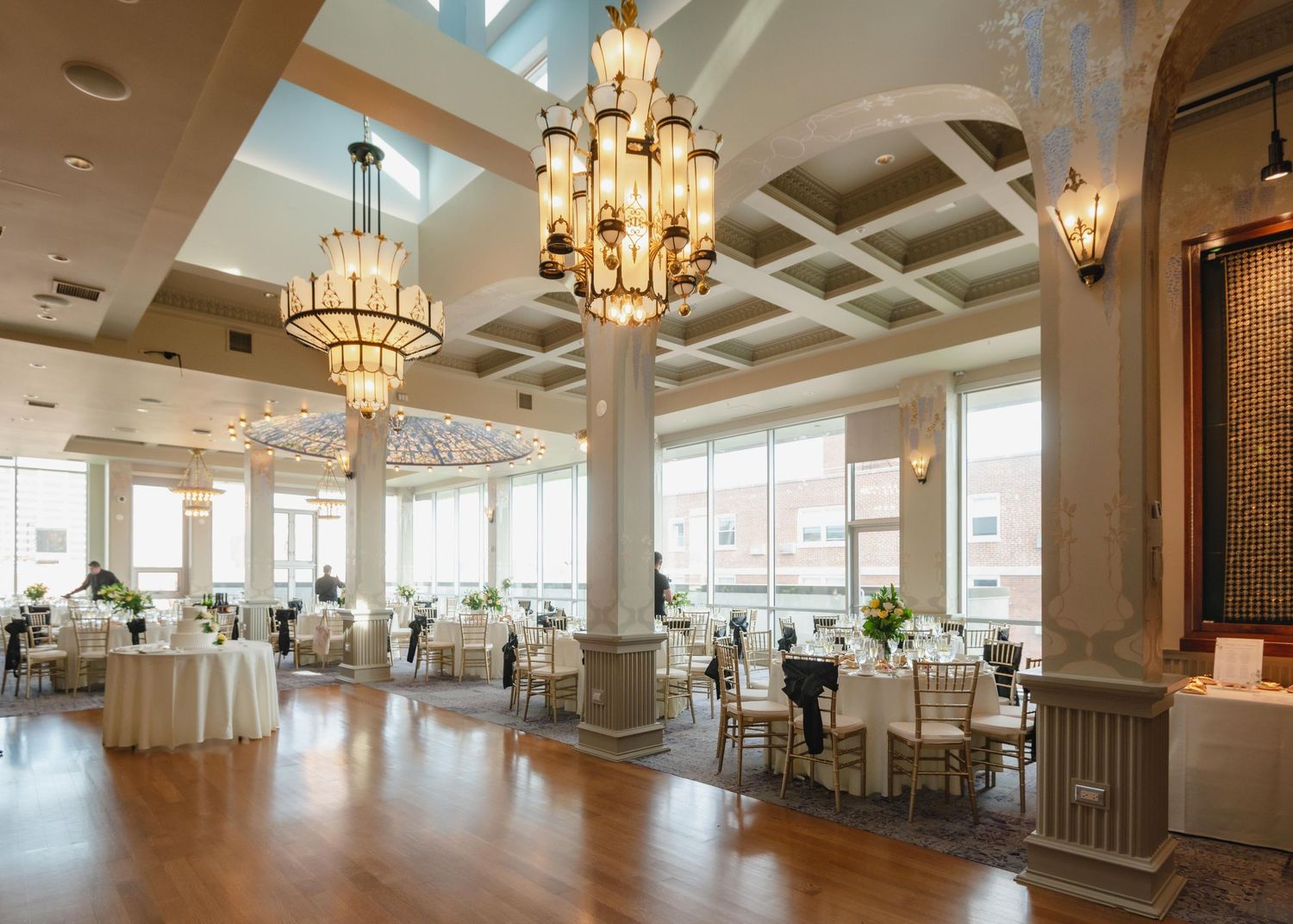 Bright modern reception venue with coffered ceilings, chandeliers and large windows.