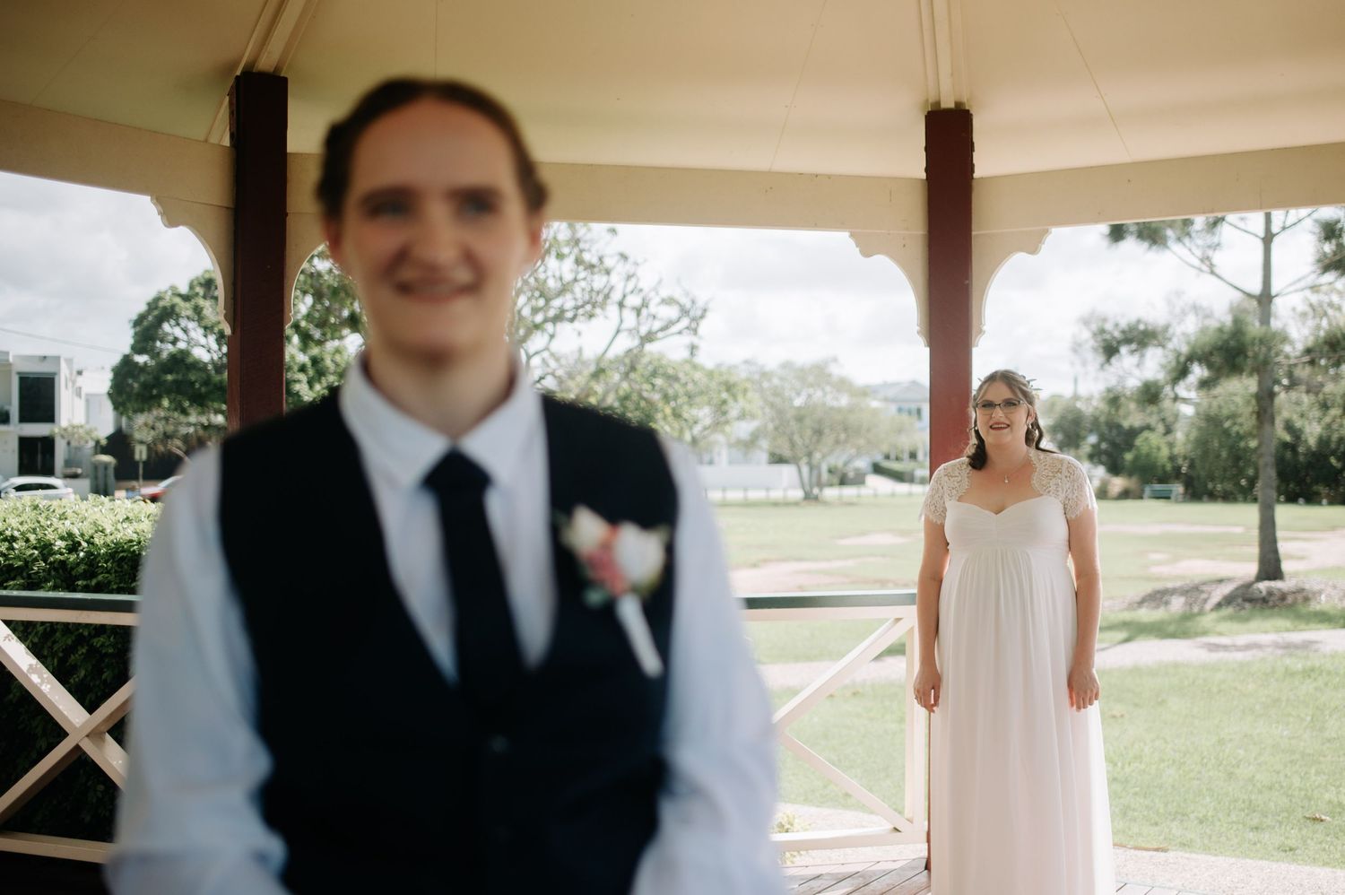 A couple sharing their first look moment under a covered outdoor porch.