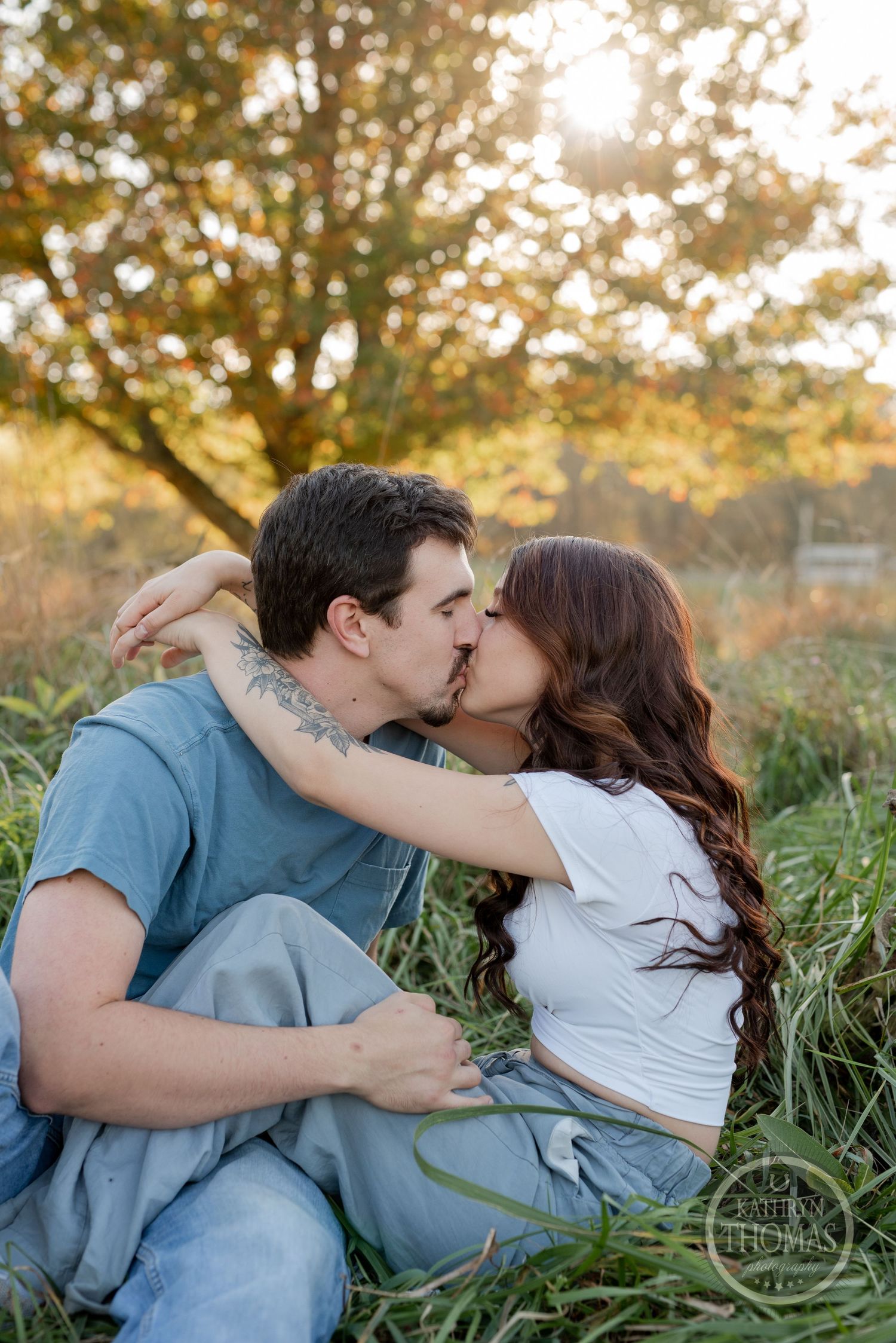 A romantic couple shares an intimate moment in a sunlit meadow during golden hour.