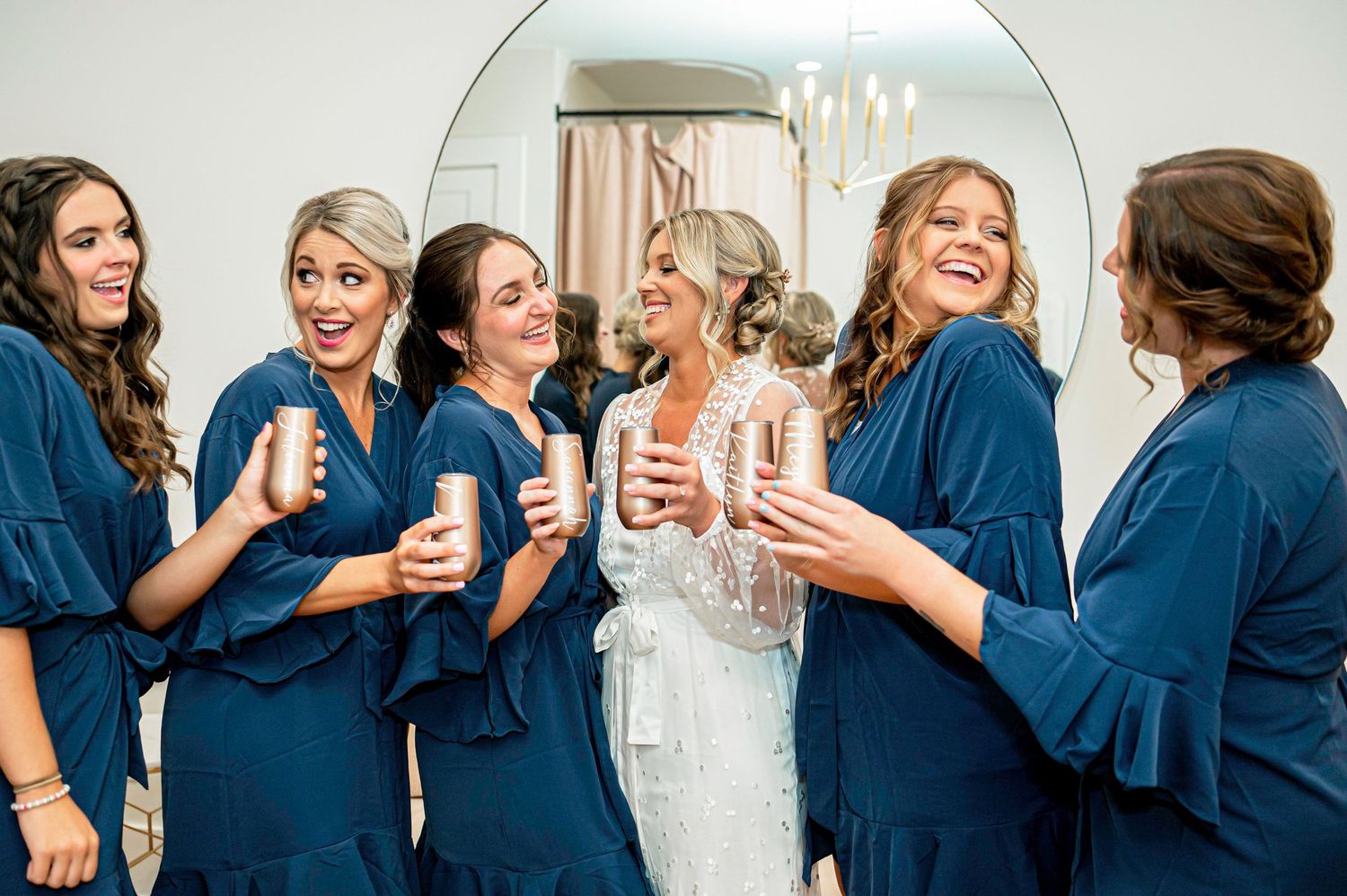 Wedding party shares champagne toast while getting ready in matching robes.