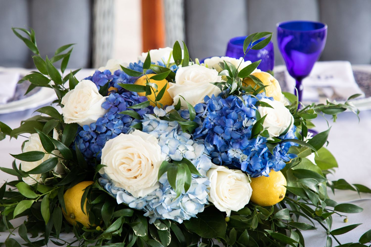 Stunning blue hydrangea, tea roses, and lemon arrangement adds charm to wedding décor